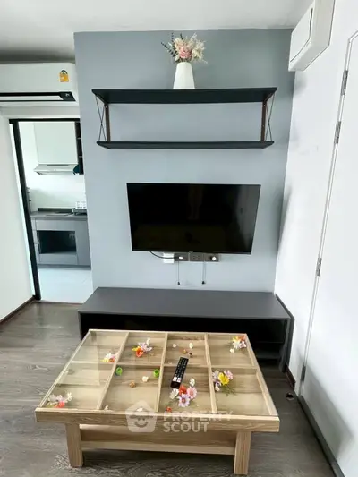 Modern living room with stylish decor and wall-mounted TV, featuring a unique coffee table and sleek shelving.