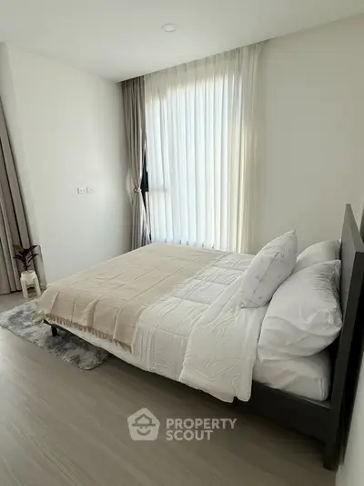 Modern bedroom with cozy bedding and natural light in a stylish apartment.