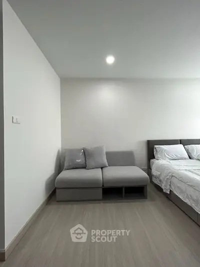Modern bedroom with sleek design and cozy gray sofa next to a comfortable bed.