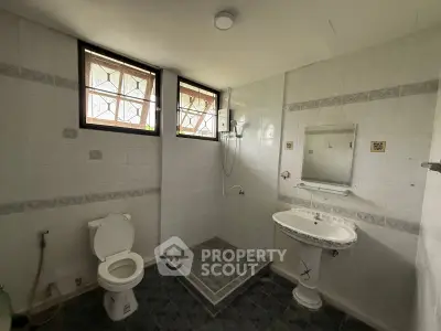 Spacious bathroom with elegant pedestal sink and large windows for natural light.