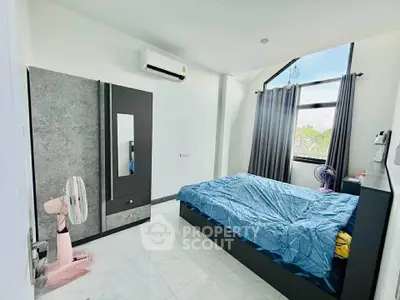 Modern bedroom with large window and air conditioning, featuring sleek furniture and natural light.