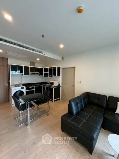 Modern open-layout living room with sleek black kitchen and stylish furniture.