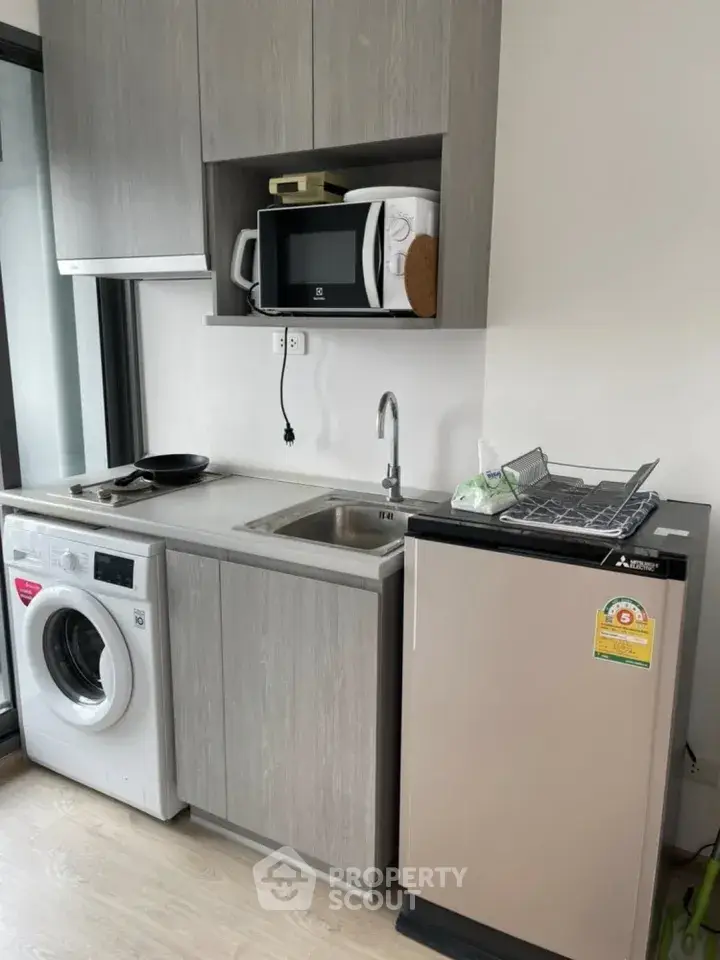 Modern compact kitchen with washing machine and microwave in sleek apartment