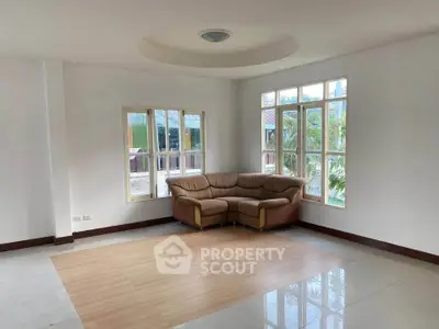 Spacious living room with large windows and cozy corner sofa, offering abundant natural light and serene views.