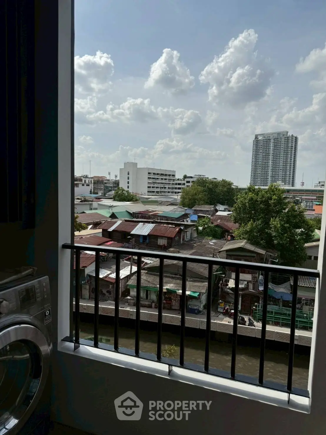 Stunning urban view from a balcony with a washing machine, showcasing cityscape and skyline.