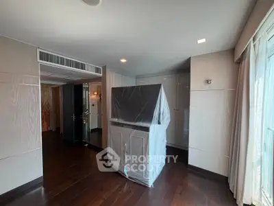 Spacious modern living room with dark wood flooring and large windows for natural light.
