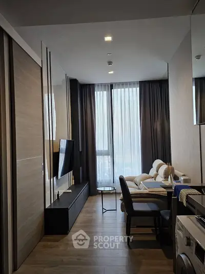 Modern living room with sleek furniture and natural light, featuring a wall-mounted TV and cozy seating area.
