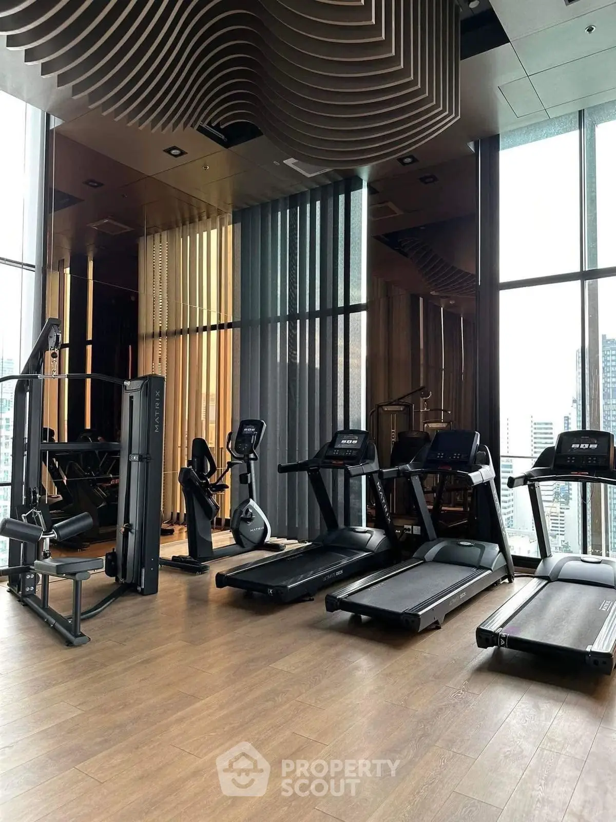 Modern gym with state-of-the-art equipment and floor-to-ceiling windows offering city views.