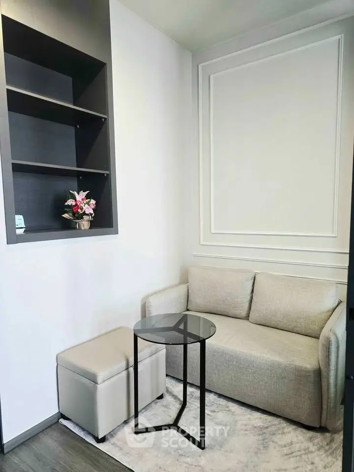 Cozy living room with modern sofa, glass table, and decorative shelving in a stylish apartment.