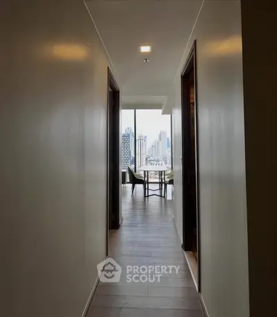 Modern apartment hallway leading to a bright room with city view