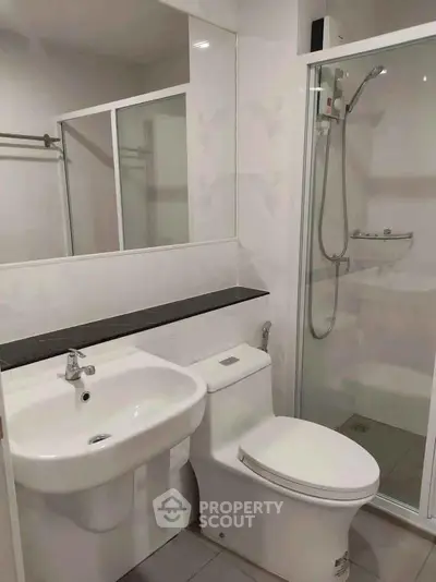 Modern bathroom with sleek fixtures and glass shower enclosure in a contemporary apartment.