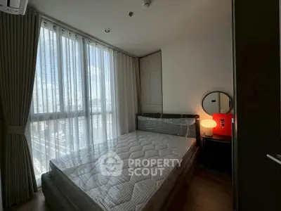 Cozy bedroom with large window and modern furnishings in a high-rise apartment.