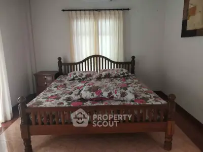 Cozy bedroom with wooden bed frame and floral bedding, perfect for a restful retreat.