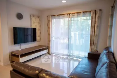 Modern living room with sleek leather sofa and wall-mounted TV, featuring large windows with elegant curtains.