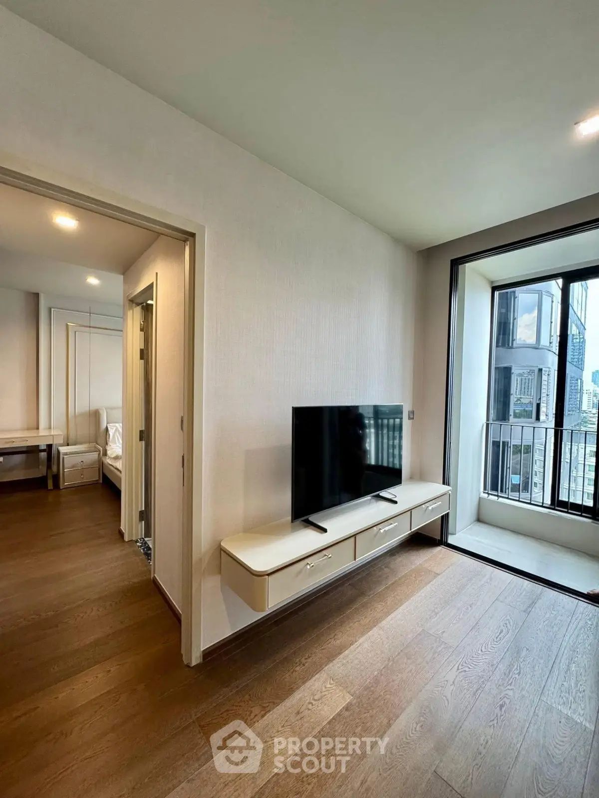 Modern apartment interior with sleek TV setup and balcony view
