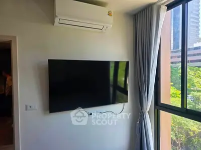 Modern living room with wall-mounted TV and large window offering city view.