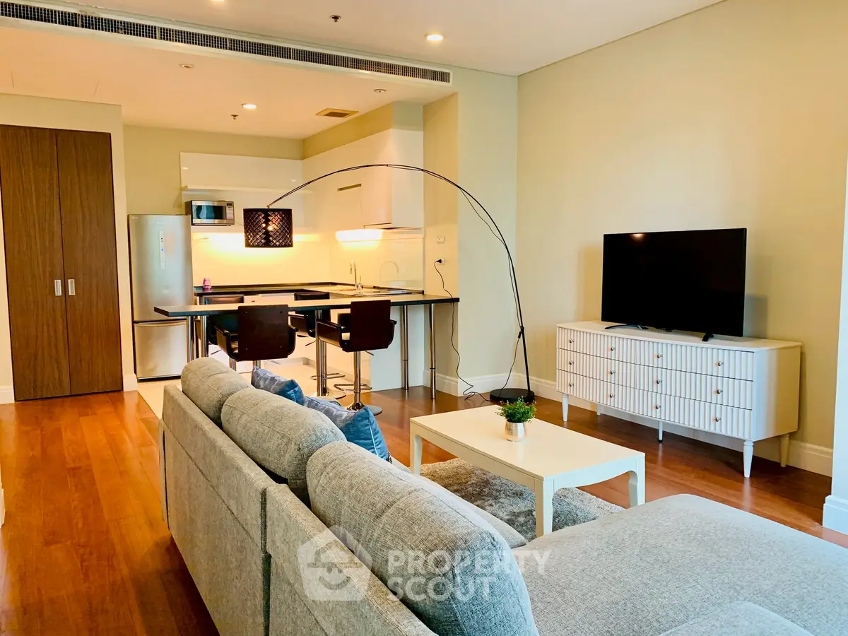Modern living room with open kitchen, stylish furniture, and cozy ambiance.