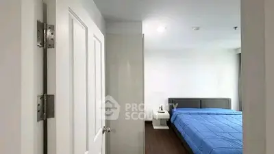 Modern bedroom with blue bedding and sleek furniture in a bright, minimalist design.