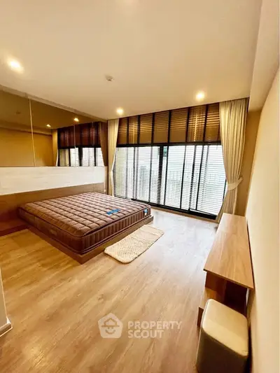 Spacious bedroom with large windows and modern furnishings in a stylish apartment.