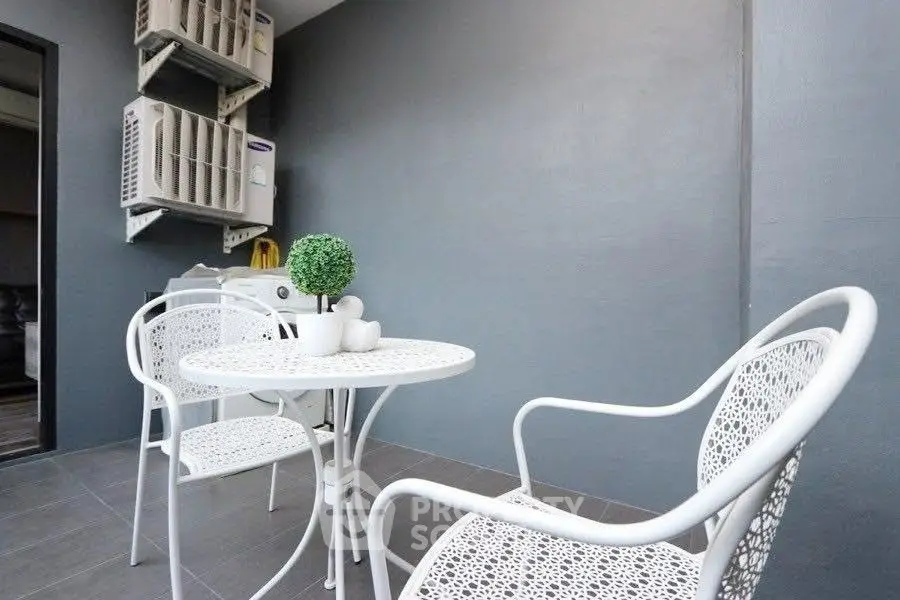 Chic outdoor balcony with modern white furniture and air conditioning units.
