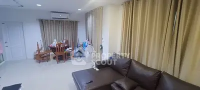 Spacious living room with leather sofa and dining area, perfect for family gatherings.