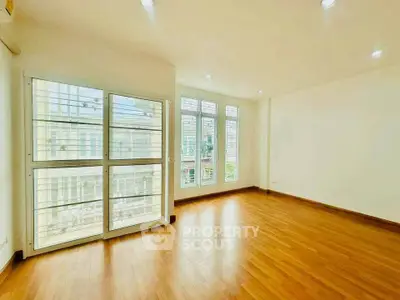 Spacious empty room with large windows and wooden flooring, perfect for customization.