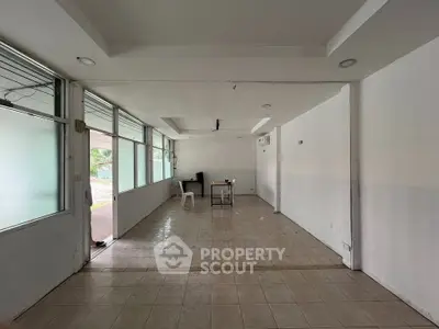 Spacious empty room with tiled flooring and large windows, ideal for customization.