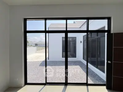 Modern home with large glass doors opening to a private courtyard, showcasing sleek architecture and ample natural light.