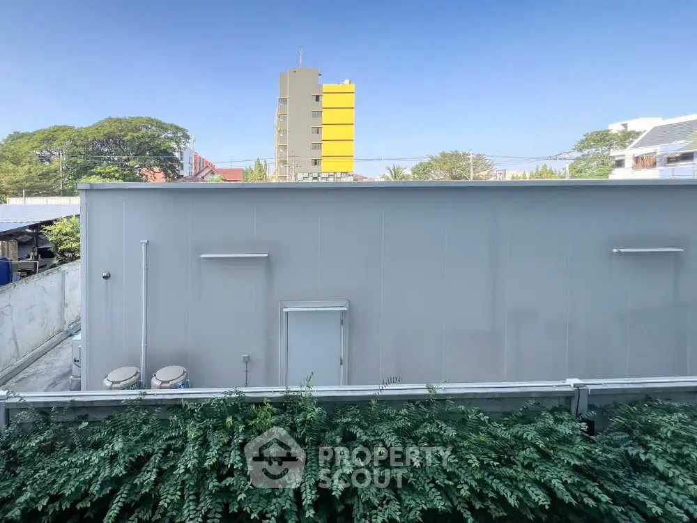 Urban building exterior with lush greenery and clear blue sky