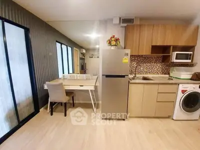 Modern kitchen with sleek appliances and dining area in open layout apartment.