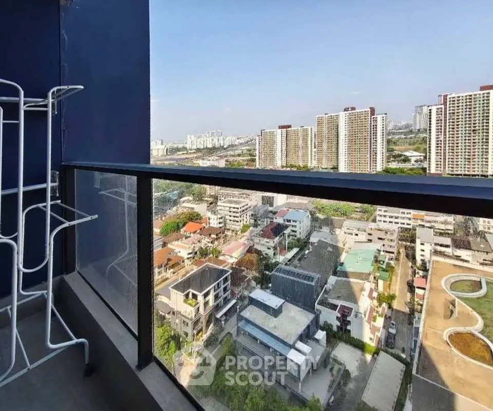 Stunning high-rise balcony view overlooking cityscape with modern buildings and clear blue sky.
