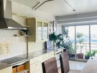 Charming kitchen with open layout and balcony view, featuring modern appliances and lush indoor plants.