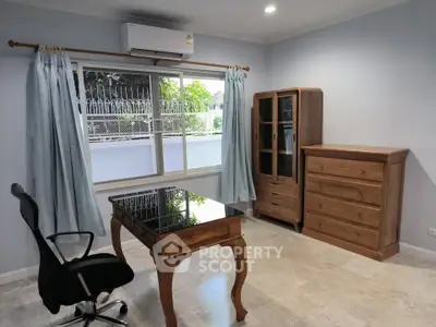 Spacious study room with elegant wooden furniture and large window view.