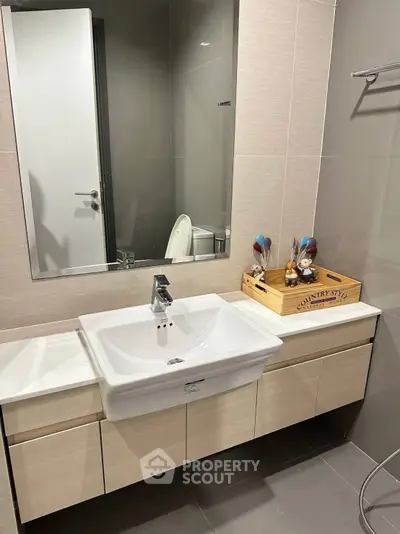 Modern bathroom with sleek vanity and large mirror in stylish apartment.