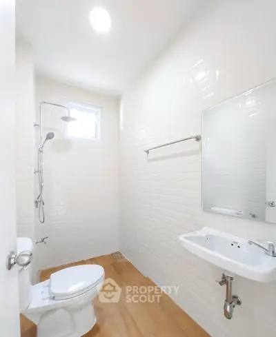 Bright and modern bathroom with white tiles and wooden flooring