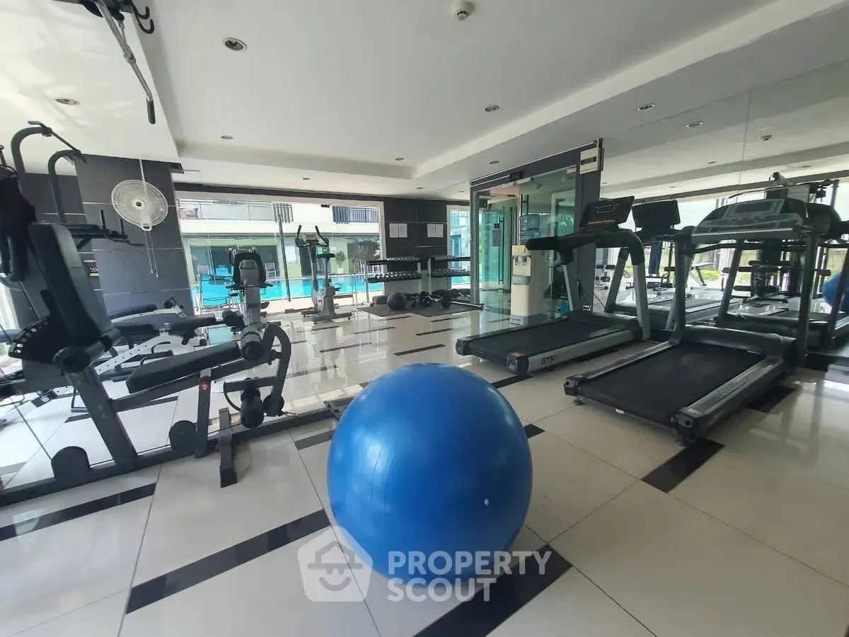Spacious modern gym with state-of-the-art equipment and pool view, perfect for fitness enthusiasts.