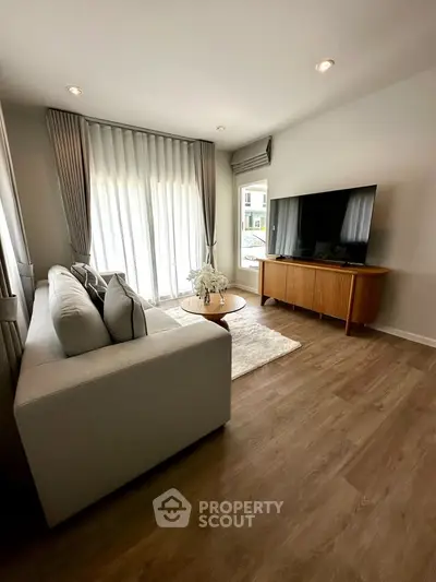 Stylish living room with modern decor, large TV, and elegant curtains, perfect for relaxation and entertainment.