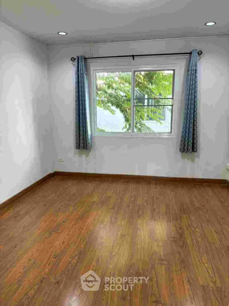 Spacious empty room with wooden flooring and large window view