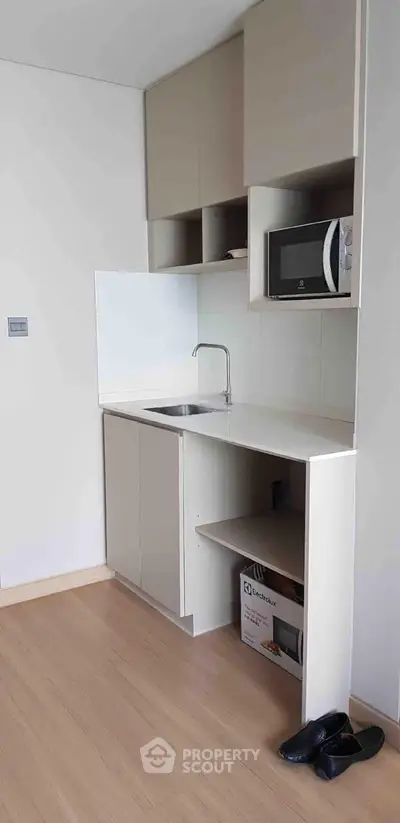 Modern compact kitchen with sleek cabinetry and built-in microwave, perfect for urban living.