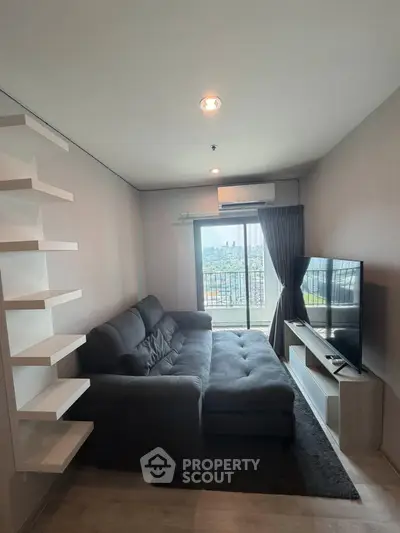 Modern living room with large sofa and city view from window, perfect for relaxation and entertainment.