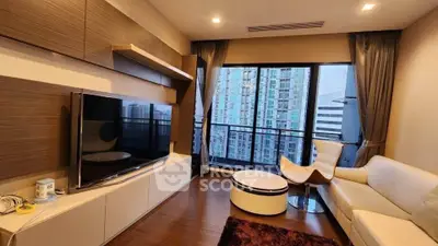 Modern living room with large TV, stylish furniture, and city view through expansive windows.