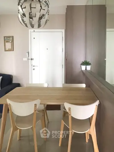 Modern dining area with wooden table and chairs, stylish lighting, and minimalist decor.