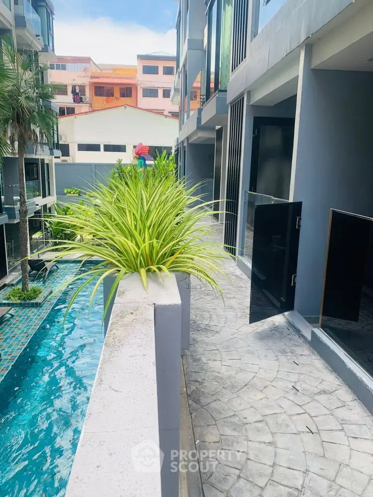 Modern apartment complex with poolside view and lush greenery