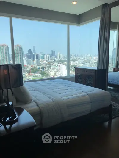 Luxurious bedroom with stunning city skyline view from large windows.