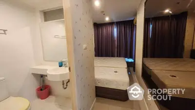 Compact bedroom with ensuite bathroom, featuring large mirror and cozy ambiance.