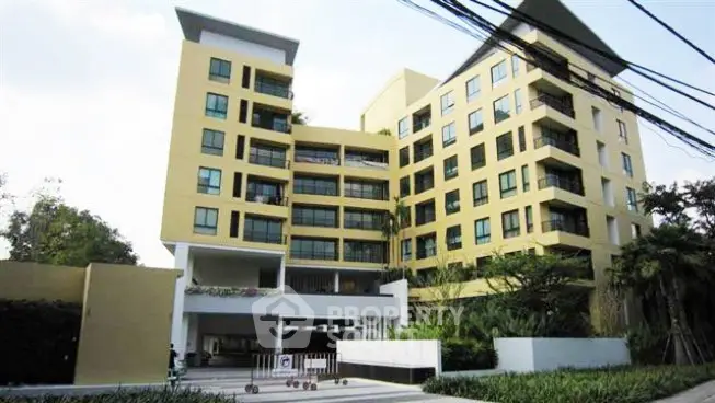 Modern apartment building with lush greenery and spacious balconies in urban setting.