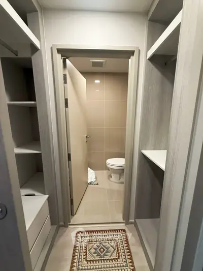 Modern bathroom with sleek design and walk-in closet, featuring neutral tones and contemporary fixtures.