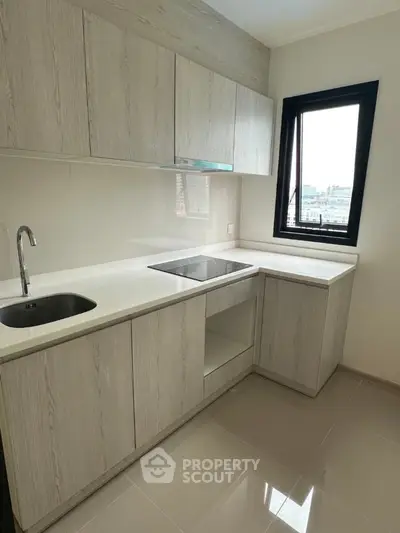 Modern kitchen with sleek cabinetry and large window offering city views.