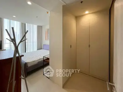 Modern bedroom with natural light and minimalist design, featuring a cozy bed and sleek wardrobe.