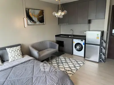 Modern studio apartment with sleek kitchen and cozy living area, featuring stylish decor and compact appliances.